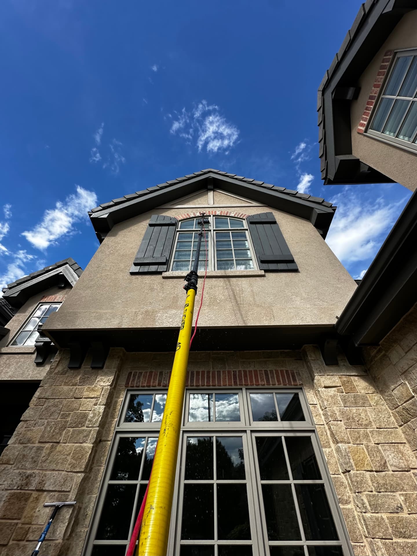 Technician using a water-fed pole on upper-story residential windows