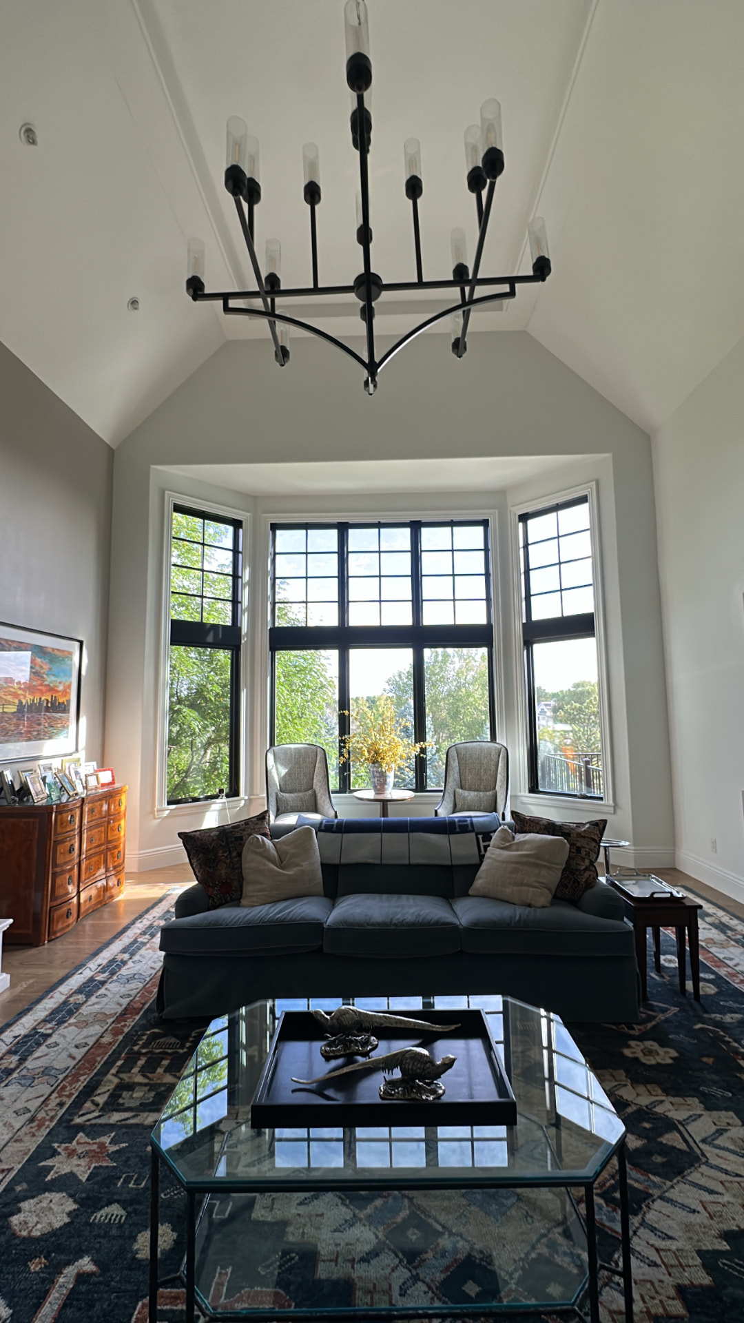 Great room with a two-story wall of glass overlooking landscaped grounds
